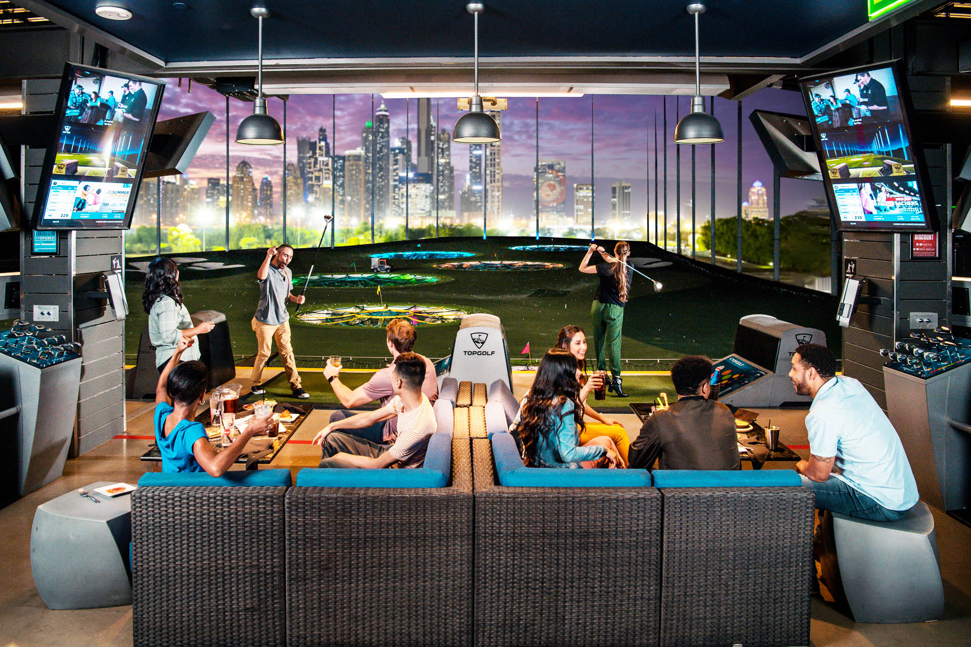 Guests enjoying a Topgolf Dubai hitting bay at night